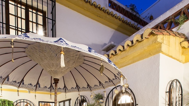 Un patio exterior con una zona de estar cubierta, una mesa de comedor y plantas en macetas.