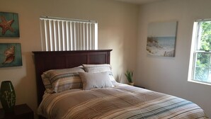 A bedroom with a bed, a nightstand, a window, and wall decorations.