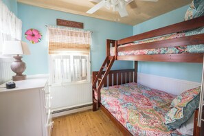 A bunk bed room with a window, a lamp, and a quote on the wall.