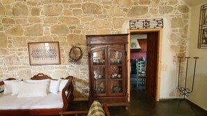 A room with a stone wall, a wooden bed, a cabinet with glass doors, and a television on a stand.