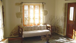 A cozy room with a wooden bench, a cushioned bench, and a vase with dried flowers.