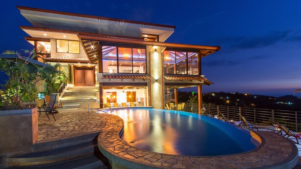 Une maison moderne à deux étages, dotée d’une piscine, d’un espace extérieur aménagé et offrant une vue sur le paysage.