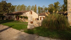 Un edificio rústico de piedra con tejado de tejas, rodeado de follaje y árboles.