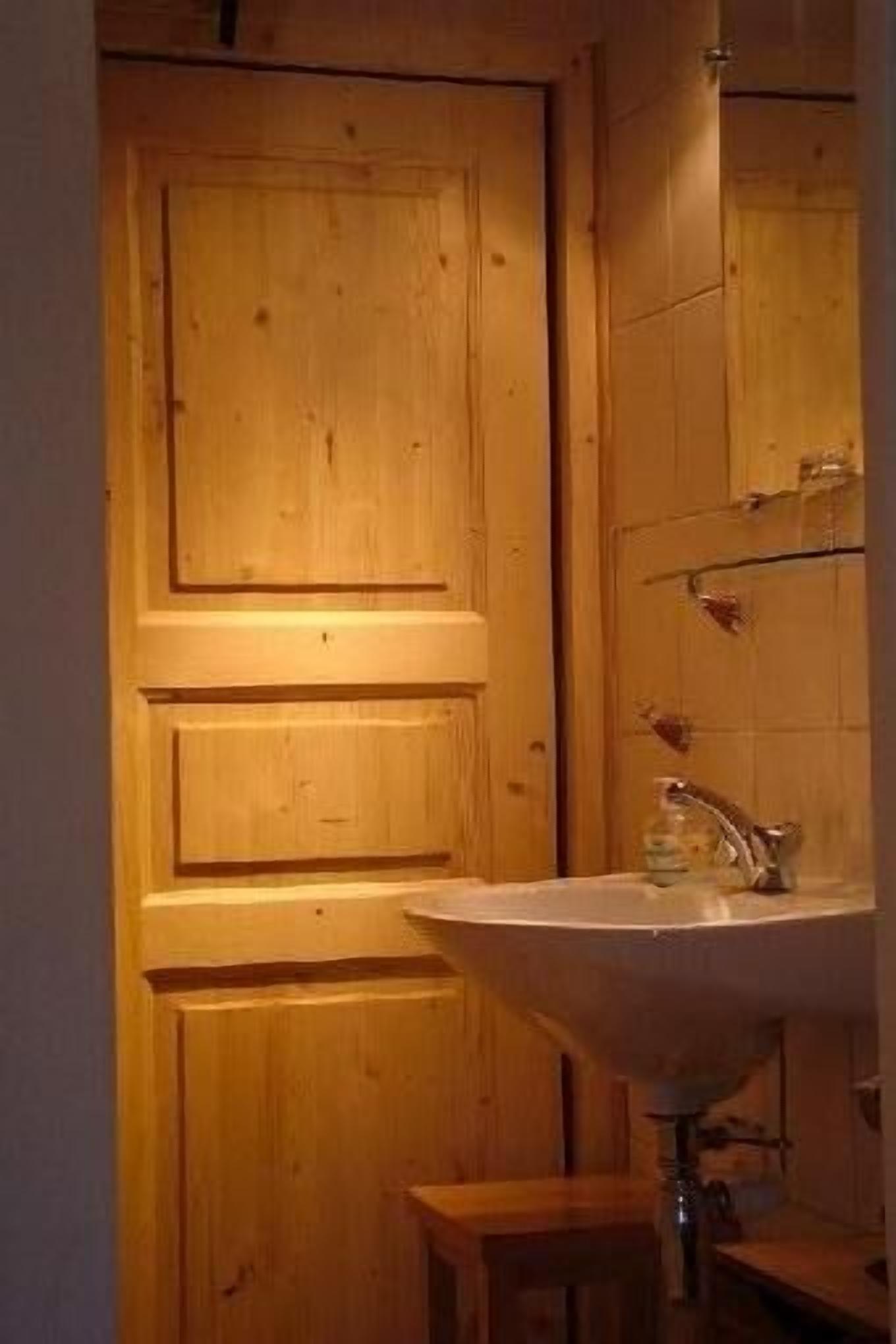 Una puerta de madera con un espejo sobre un lavabo.