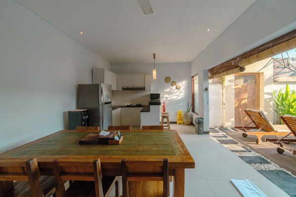 A modern kitchen with white cabinets, a built-in microwave, and a stainless steel refrigerator. - Villa Raka (Seminyak)