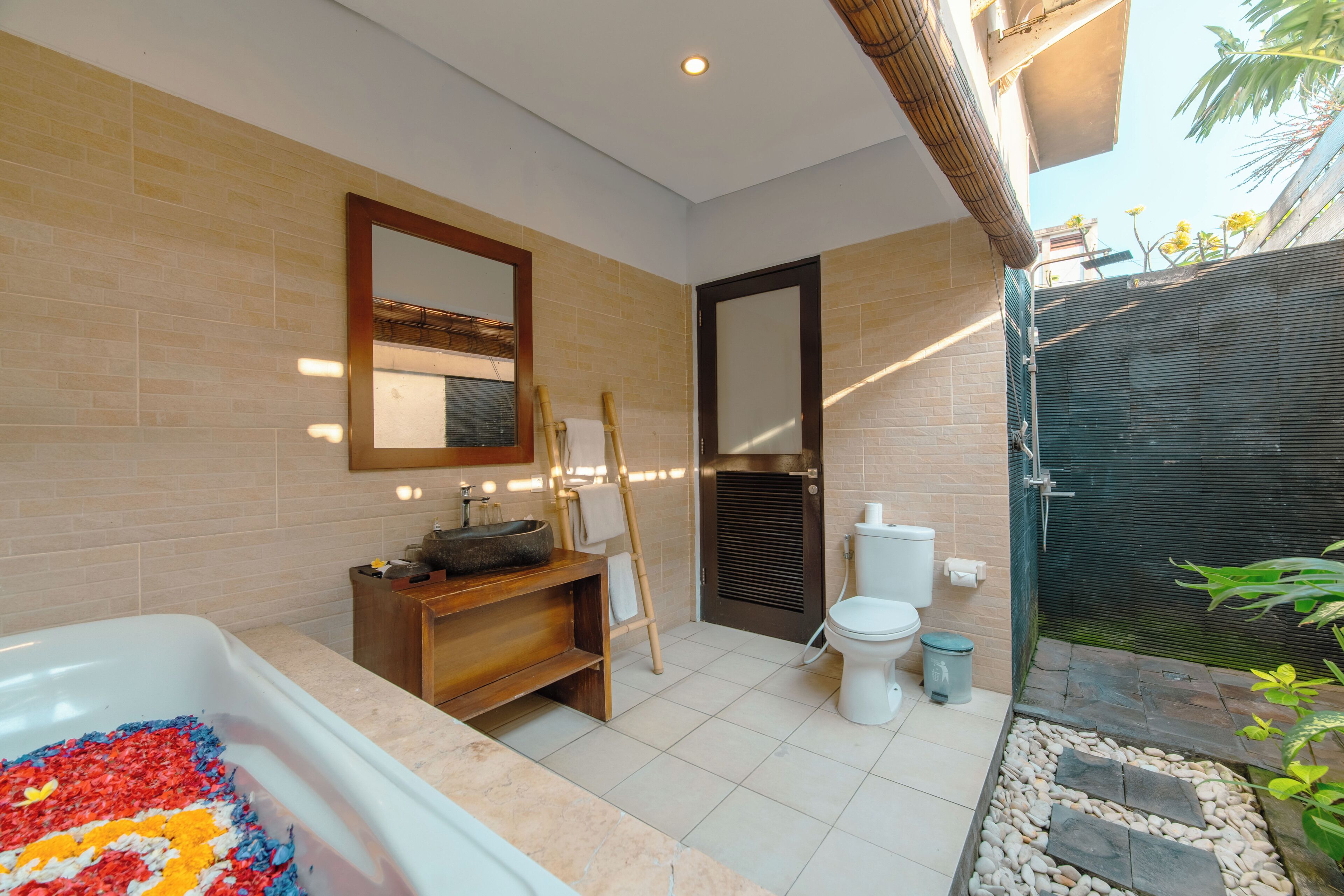 A modern bathroom with a bathtub, a wooden vanity, a toilet, and a shower area.