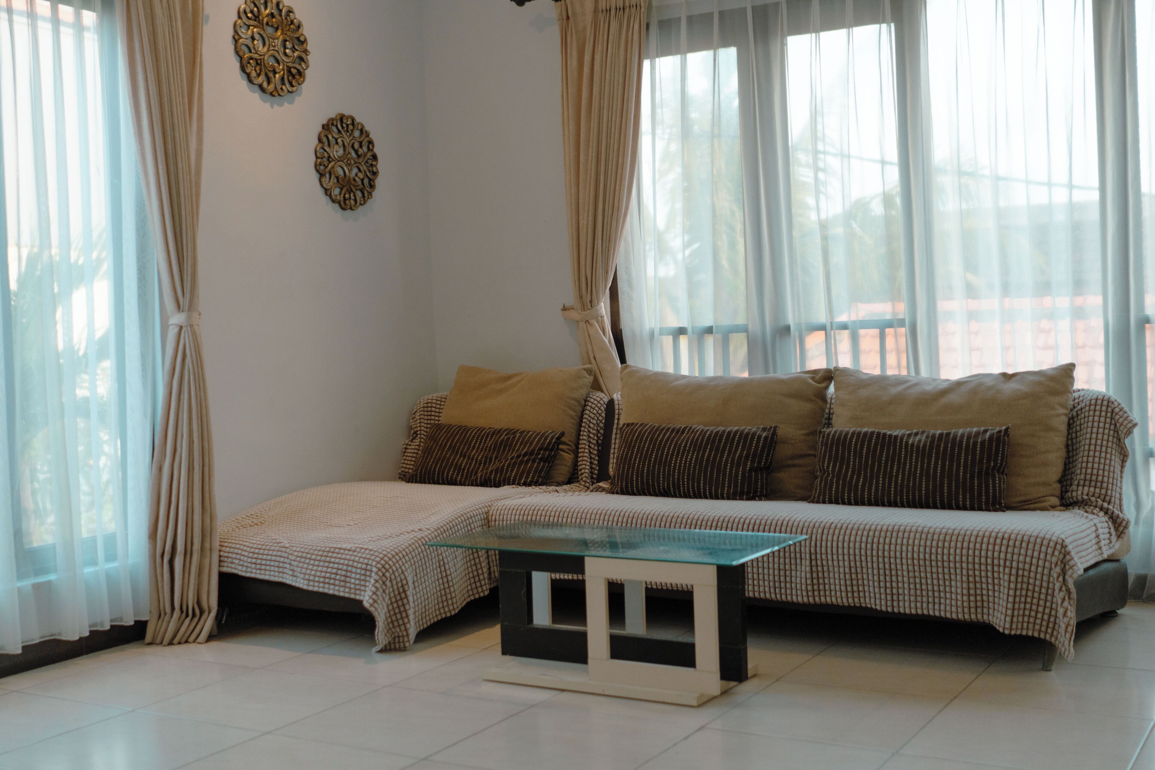 A living room with a sofa, a glass coffee table, and curtains.