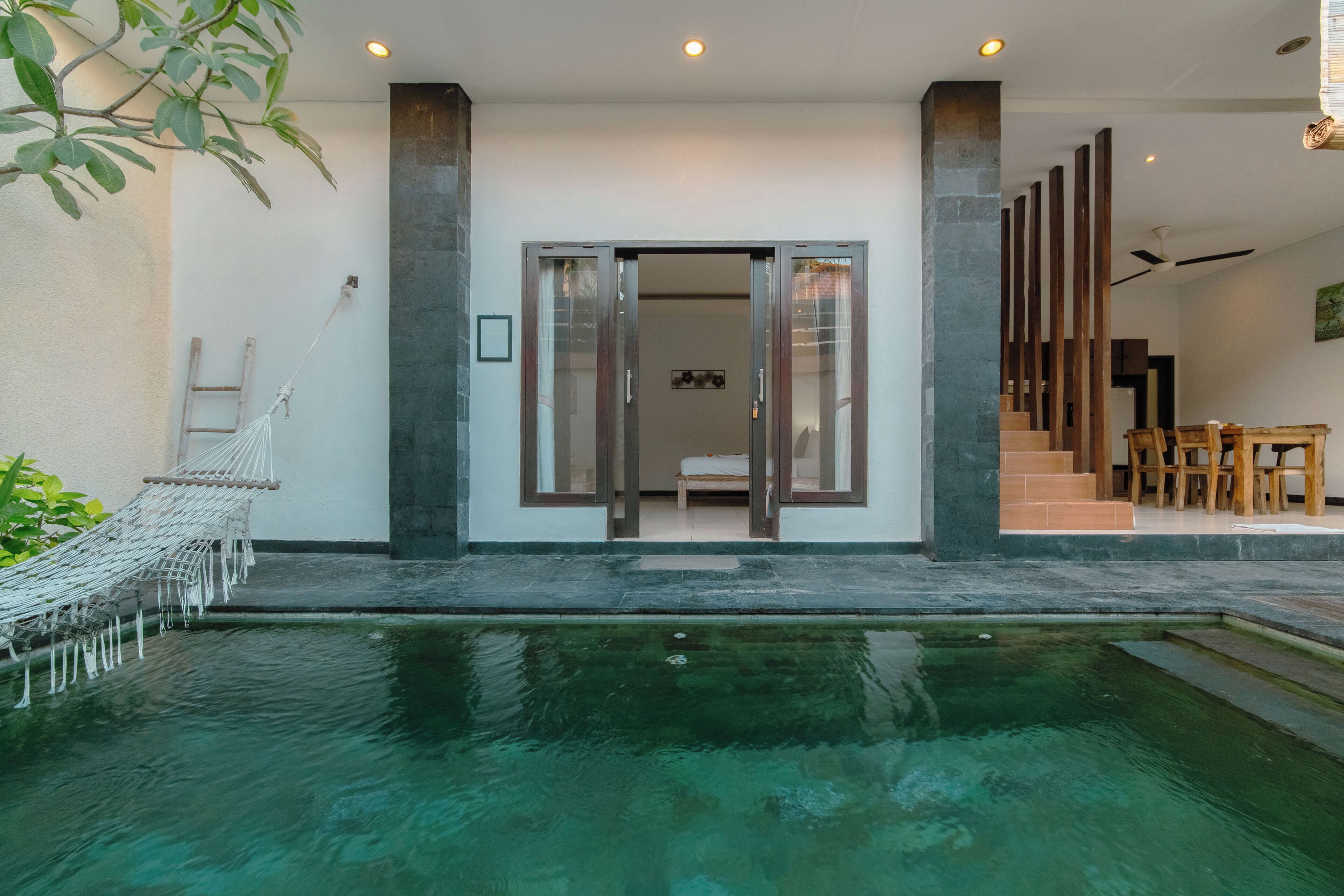 Ein modernes Haus mit Schwimmbad, Treppe und Essbereich.