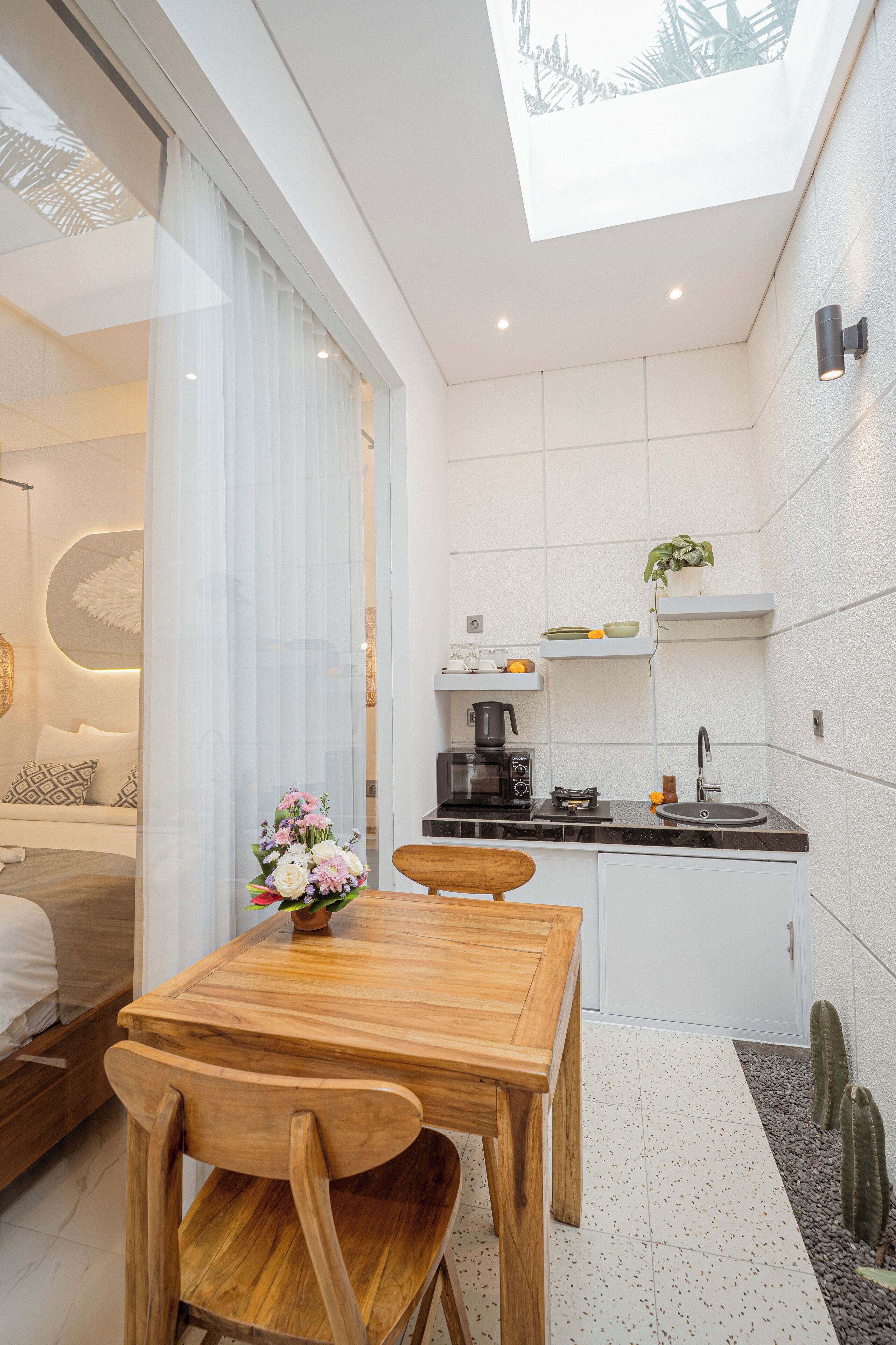 Una cocina moderna con comedor, que incluye una mesa y sillas de madera, una cafetera y una planta pequeña en la encimera.