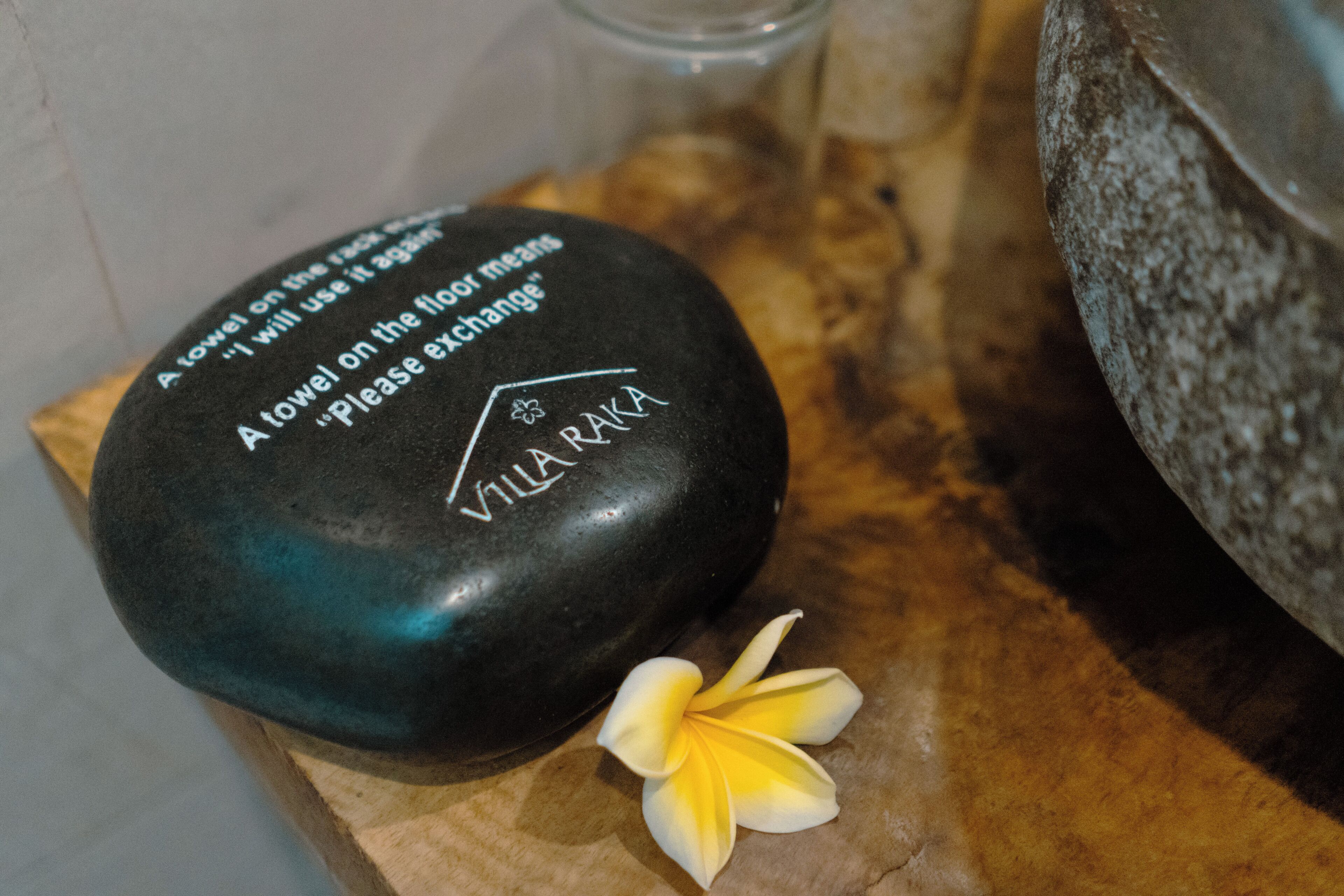 A stone with inscriptions and a flower on a wooden surface.