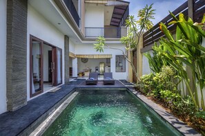Ein modernes Haus mit Swimmingpool, Balkon und üppiger Bepflanzung.