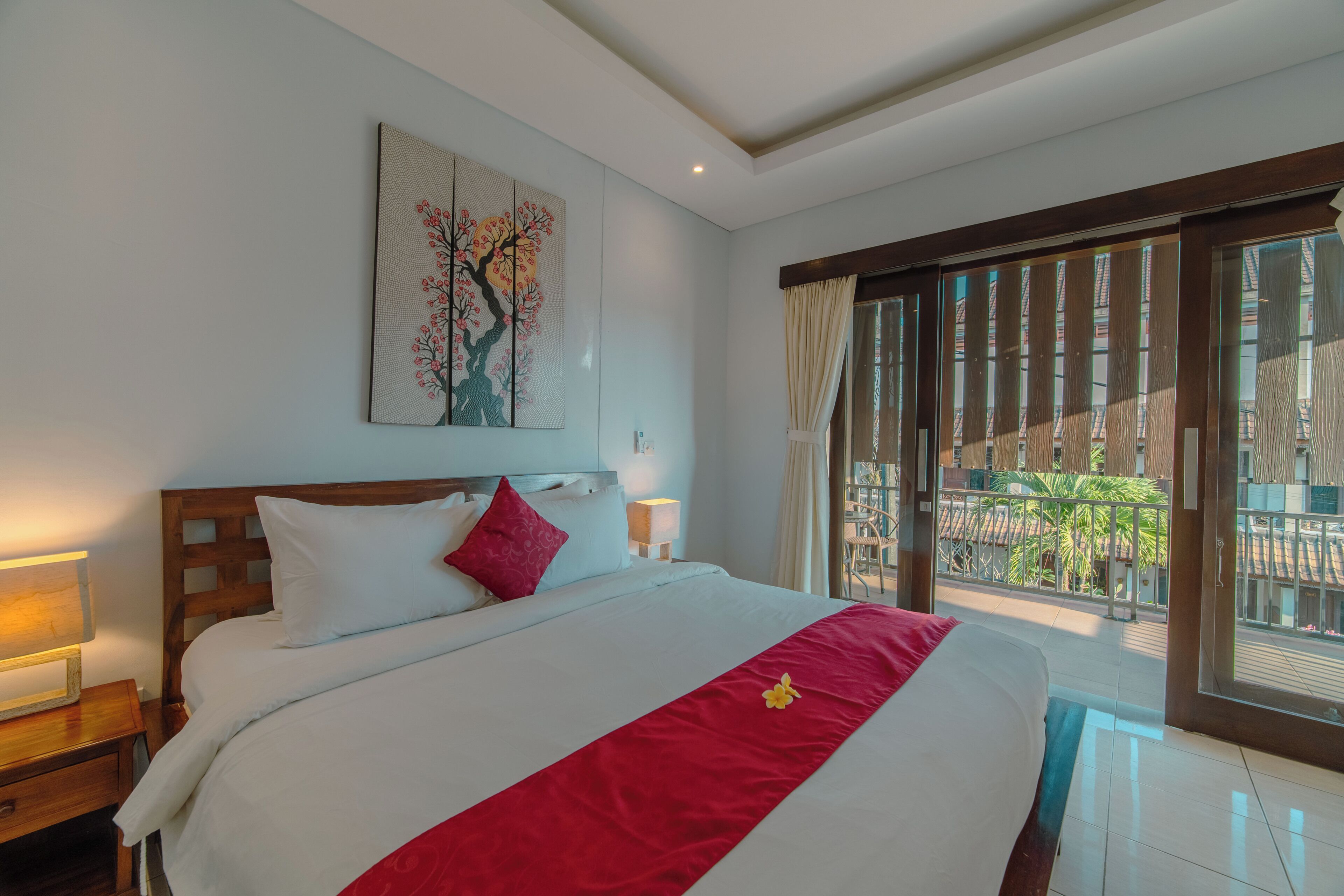 Een hotelkamer met een groot bed, een nachtkastje, een kunstwerk aan de muur en uitzicht naar buiten.
