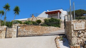 A villa with a stone wall, a metal gate, and a sign reading "Villa Elena".