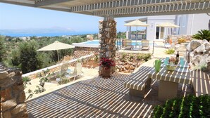 A rooftop terrace with a pool, lounge chairs, and a stone pillar.