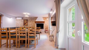 Un salon chaleureux avec une cheminée en pierre, des meubles en bois et une grande fenêtre agrémentée de rideaux.