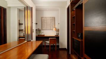 Una habitación de hotel moderna con un escritorio de madera, una silla, un banco, una estantería y un espejo grande.