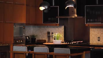Una cocina moderna con armarios de madera, una isla central, dos lámparas colgantes y un ventilador de techo.