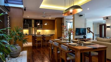 Una cocina moderna con armarios de madera, un comedor con mesa y sillas de madera, y una sala de estar con sofá y televisor.