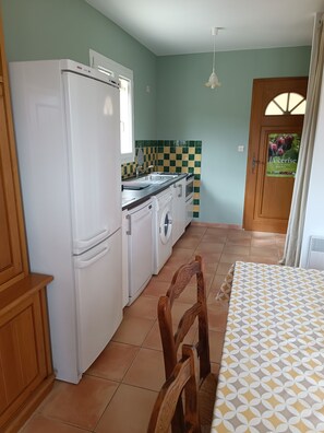 Compact kitchen with modern appliances, dining area, and access to an outdoor space.