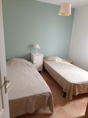 Une chambre avec deux lits simples, une table de chevet avec une lampe et un luminaire suspendu.
