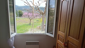 A bedroom with a large window, a bed, a wardrobe, and a radiator. - Cottage "Cherry" to METHAMIS (Méthamis)