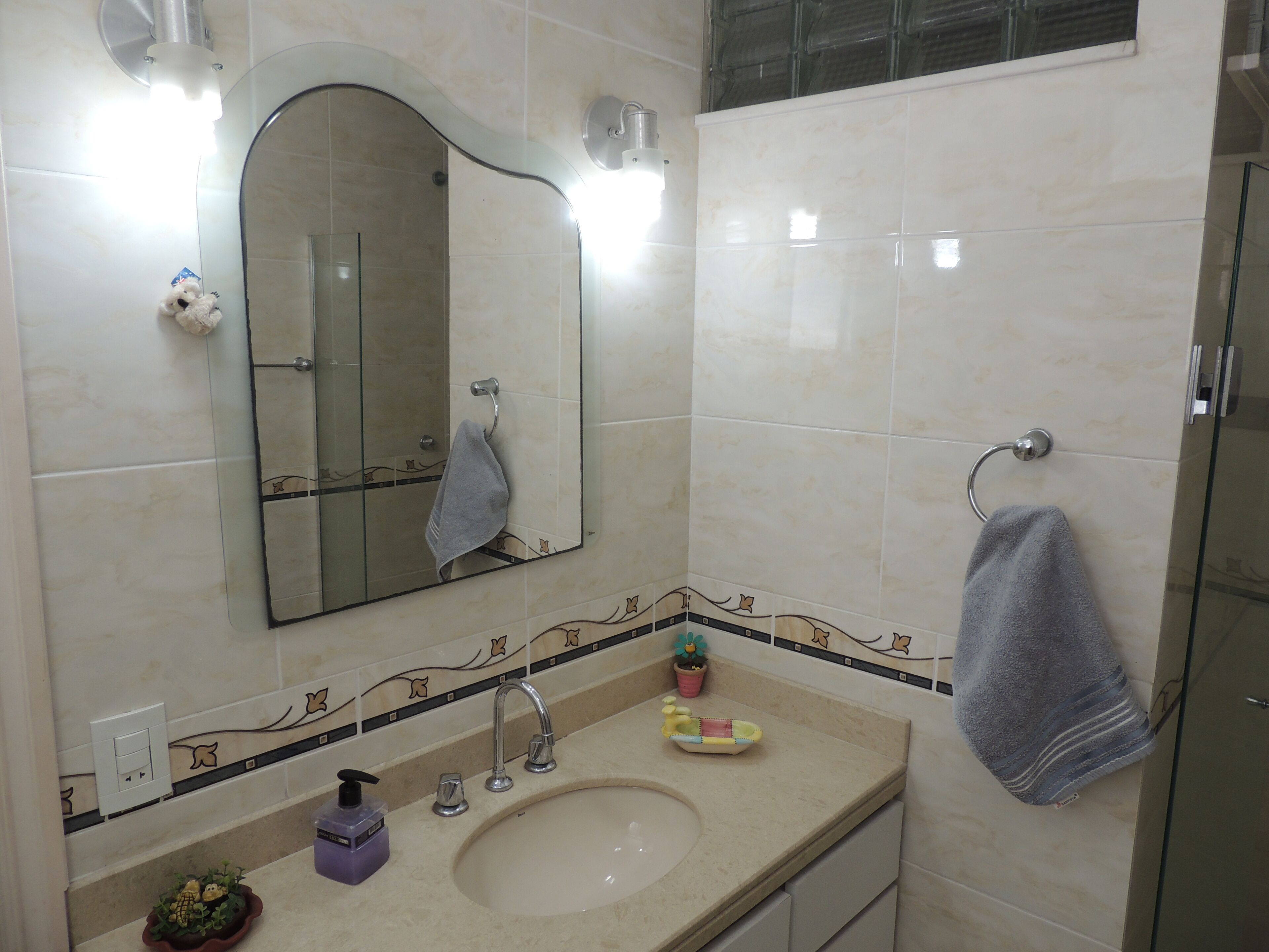 A bathroom with a sink, mirror, towel rack, and decorative tiles.