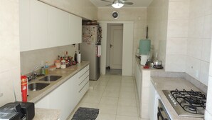 Une cuisine de taille réduite équipée d’une cuisinière à gaz, d’un réfrigérateur, d’un four à micro-ondes et d’un évier.