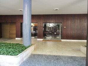 Eine Lobby mit Fliesenboden, einer großen Säule, einer geschlossenen Holztür und einem Glastürrahmen.