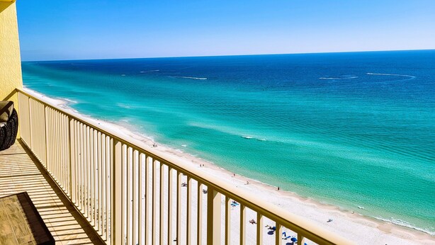 Un balcon avec vue sur une plage et l’océan.