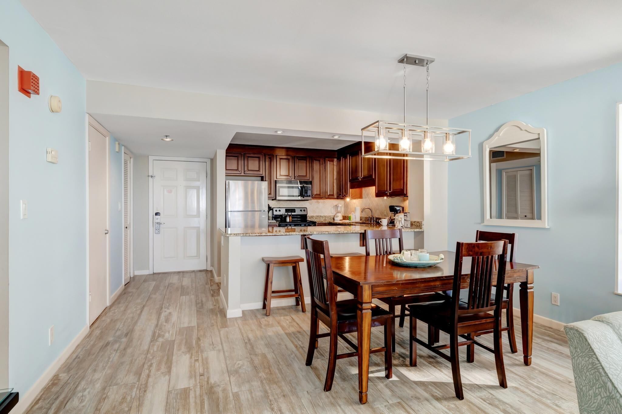 A modern kitchen with wooden cabinets, a central island, and a dining area with a wooden table and chairs.