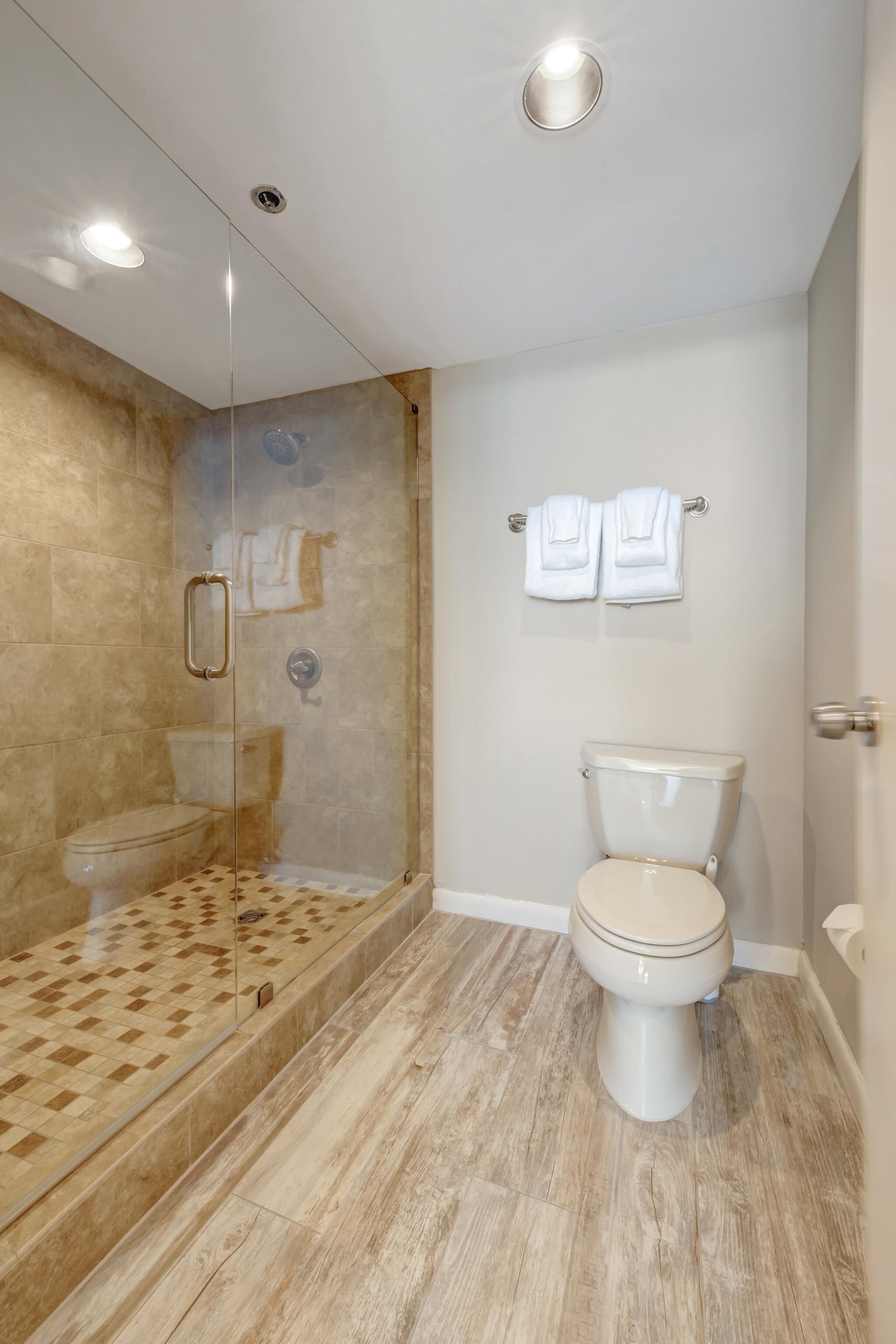 A bathroom with a glass-enclosed shower, a toilet, and a sink.