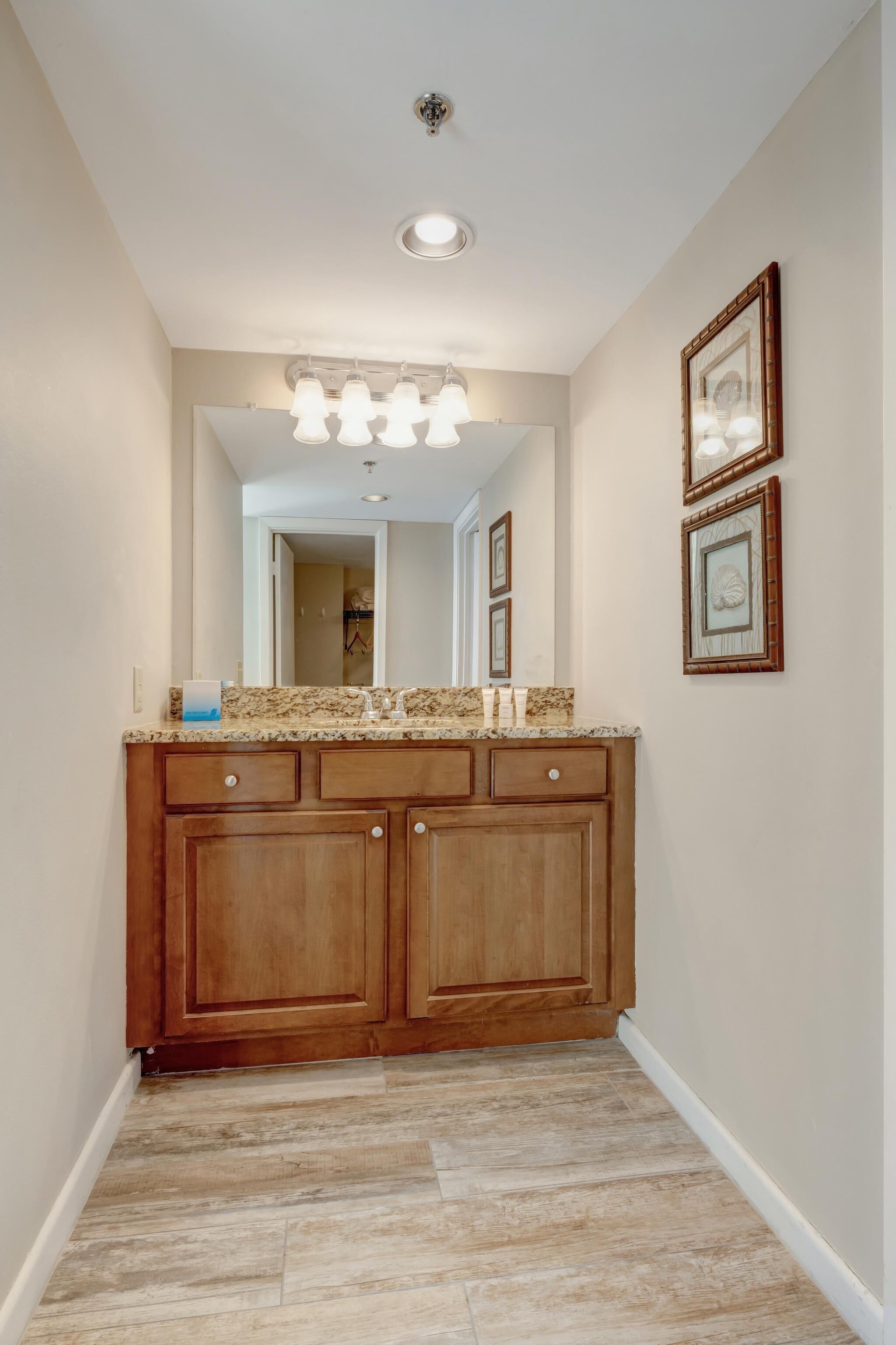 A hallway with a wooden vanity, a mirror, and framed pictures on the wall.