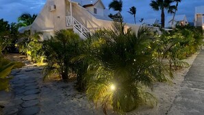 A beachfront hotel with a white facade, a staircase leading to the entrance, and palm trees in the foreground. - Appartment on the beach, exceptional sea view, condo BORA BORA (Saint-Martin)