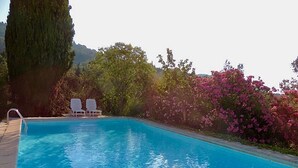 A clear blue swimming pool with two white lounge chairs and a ladder.