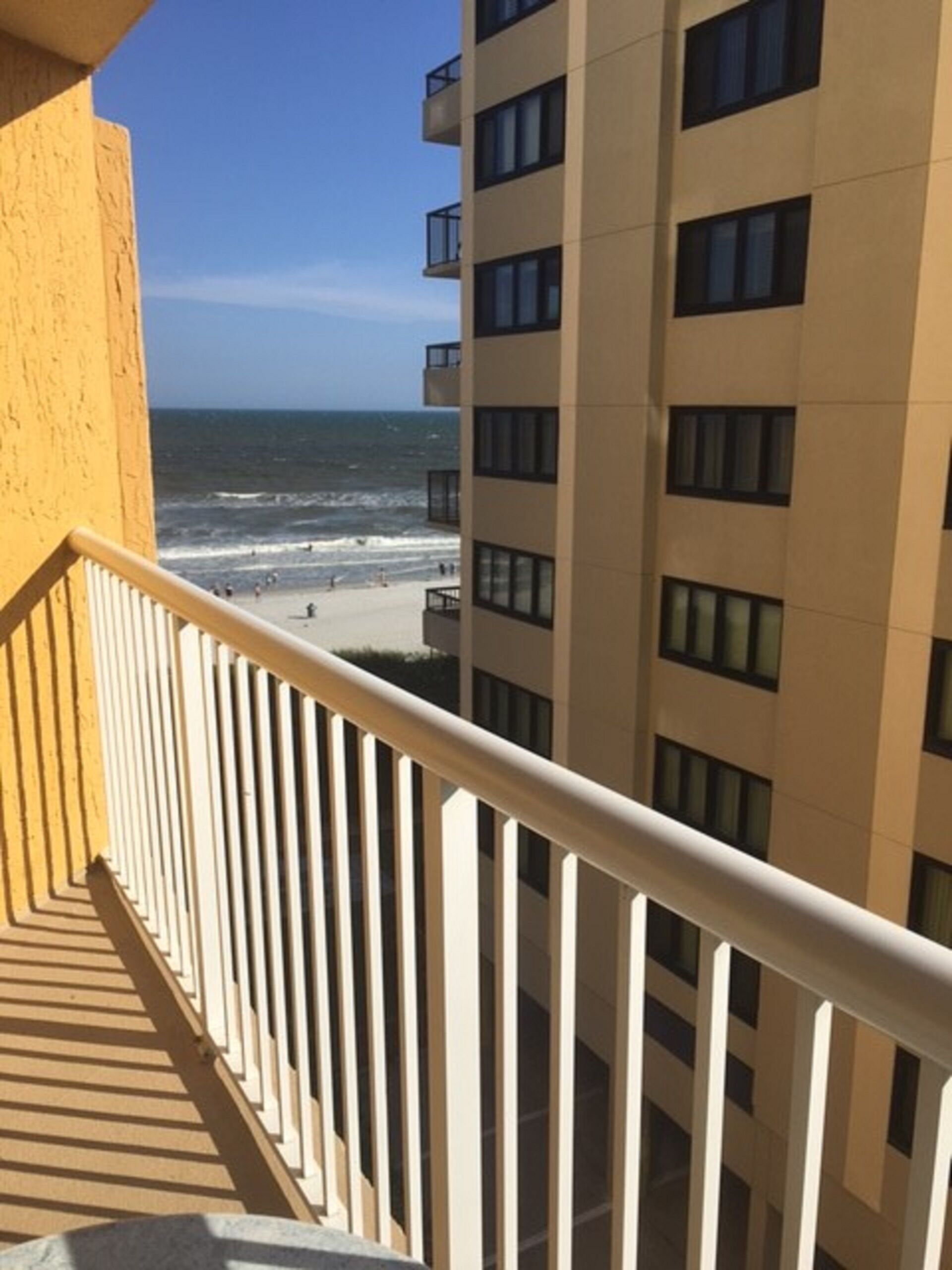 A balcony with a view of the beach and ocean.