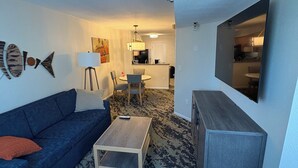 Ein Wohnzimmer mit einer Couch, einem Couchtisch, einem Fernseher und einem gemusterten Teppich.