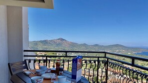 Ein Balkon mit Essplatz, der auf eine gebirgige Landschaft blickt.