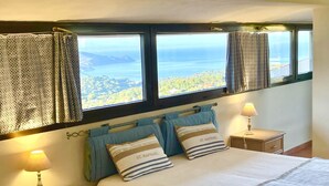 Une chambre à coucher avec un lit, deux tables de chevet, une fenêtre avec des rideaux et une vue sur un paysage.