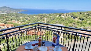 Un balcon avec une table dressée pour le petit-déjeuner, donnant sur un paysage côtier.
