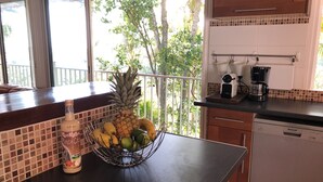 Eine Küche mit Obstschale, die eine Ananas, Bananen und Äpfel enthält, einer Kaffeemaschine und einem Geschirrspüler.