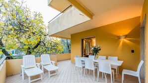 An outdoor patio with white wicker furniture and a yellow wall. - Beautiful, spacious apartment, five minutes from the castle with air conditioned (Malcesine)