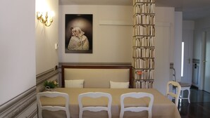 A dining area with a table set for four, a bookshelf, and a framed artwork on the wall. - Beautiful, spacious apartment, five minutes from the castle with air conditioned (Malcesine)