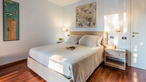 A neatly arranged bedroom with a large bed, bedside tables, and wall-mounted lamps. - Beautiful, spacious apartment, five minutes from the castle with air conditioned (Malcesine)
