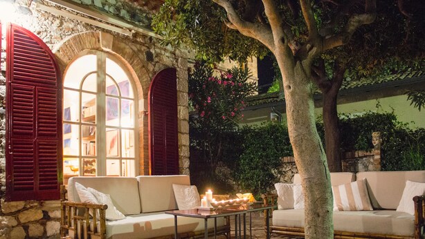 An outdoor seating area with two sofas and a table, surrounded by stone walls and greenery. - CASA OASI with view & terrace (Taormina)