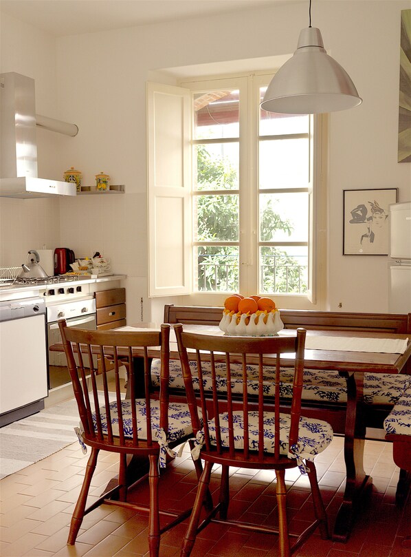 A kitchen with a dining table, chairs, and a window with a view of greenery. - CASA OASI with view & terrace (Taormina)