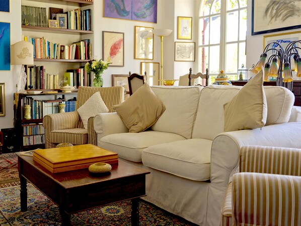 Una sala de estar con un sofá, sillones, una mesa de centro y una estantería llena de libros.