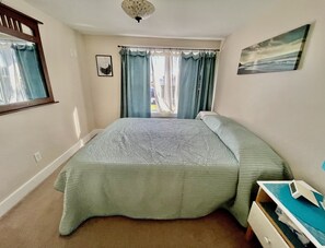 Relax in a serene bedroom with a large bed, window, and wall art.