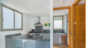 Eine moderne Küche mit einer zentralen Kochinsel, einem eingebauten Herd und einem großen Fenster.