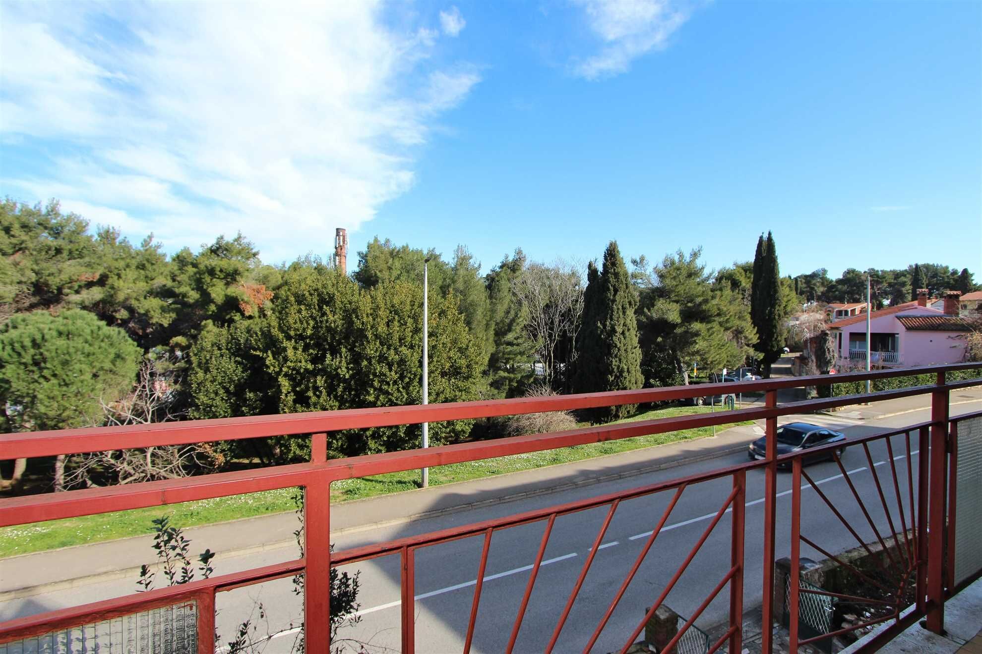 A red metal railing overlooking a road with a car passing by.