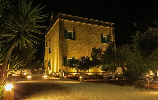 Um edifício de pedra com fachada simétrica, diversas janelas e uma área de entrada bem iluminada.